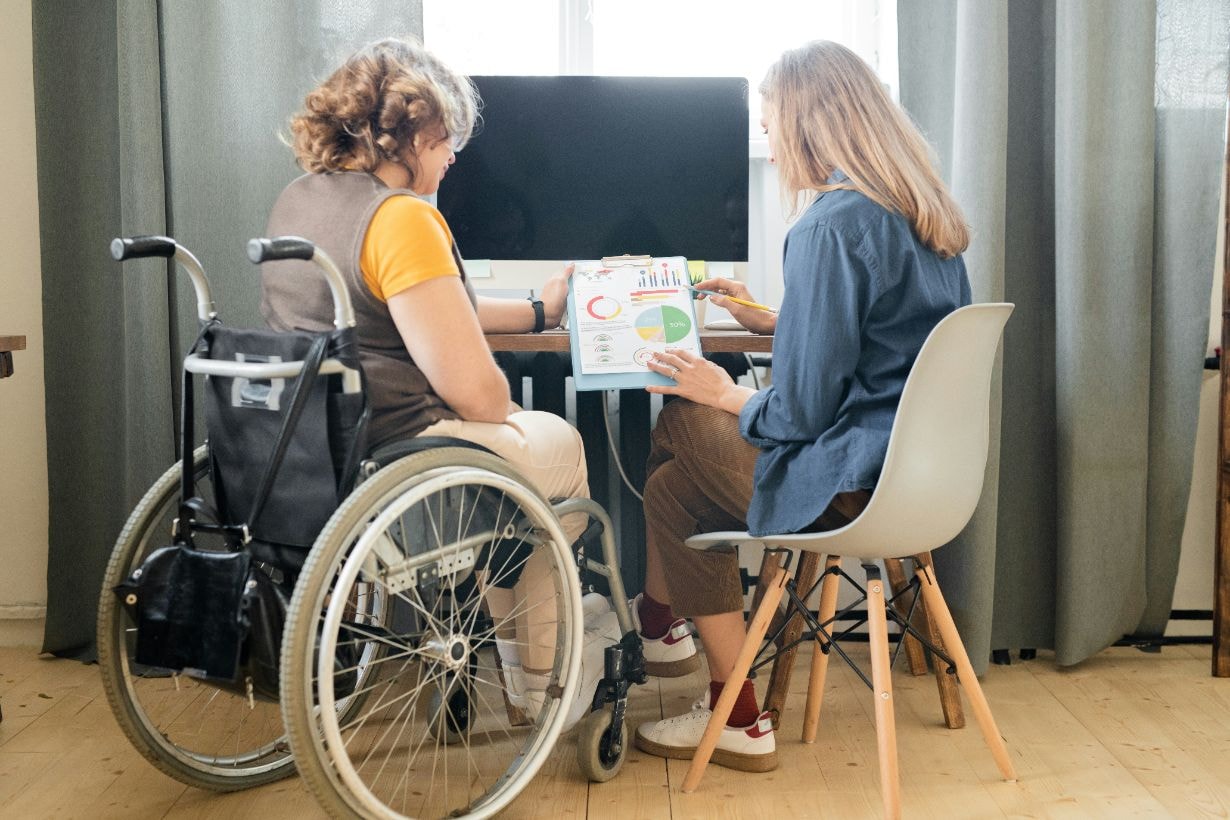 Caregiver explaining some financial data using graphs and diagrams for disabled woman