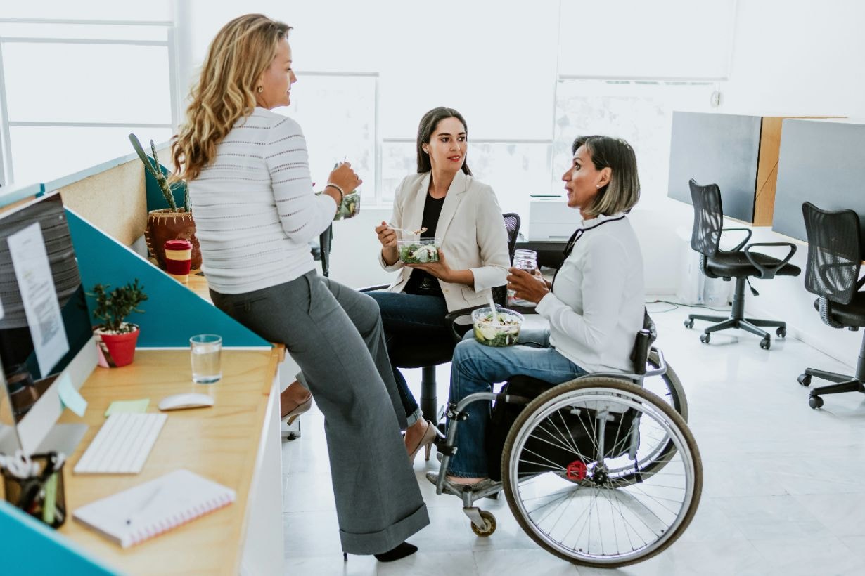 Lady in wheelchair enjoying the company of her colleagues at her workplace