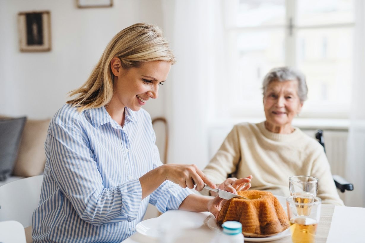 Caregiver cutting cake for the disabled woman