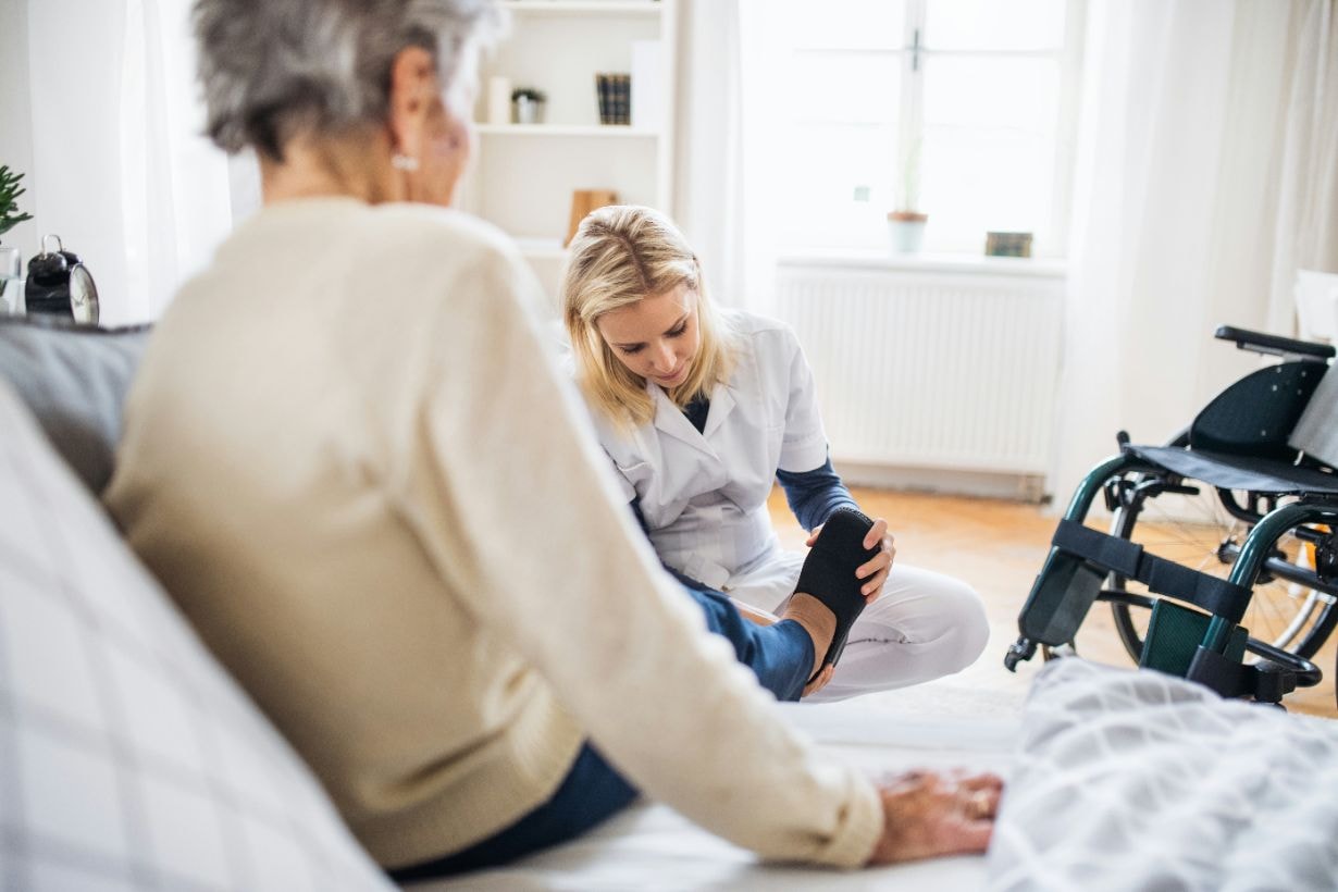 Caregiver helping disabled woman to put on her shoes