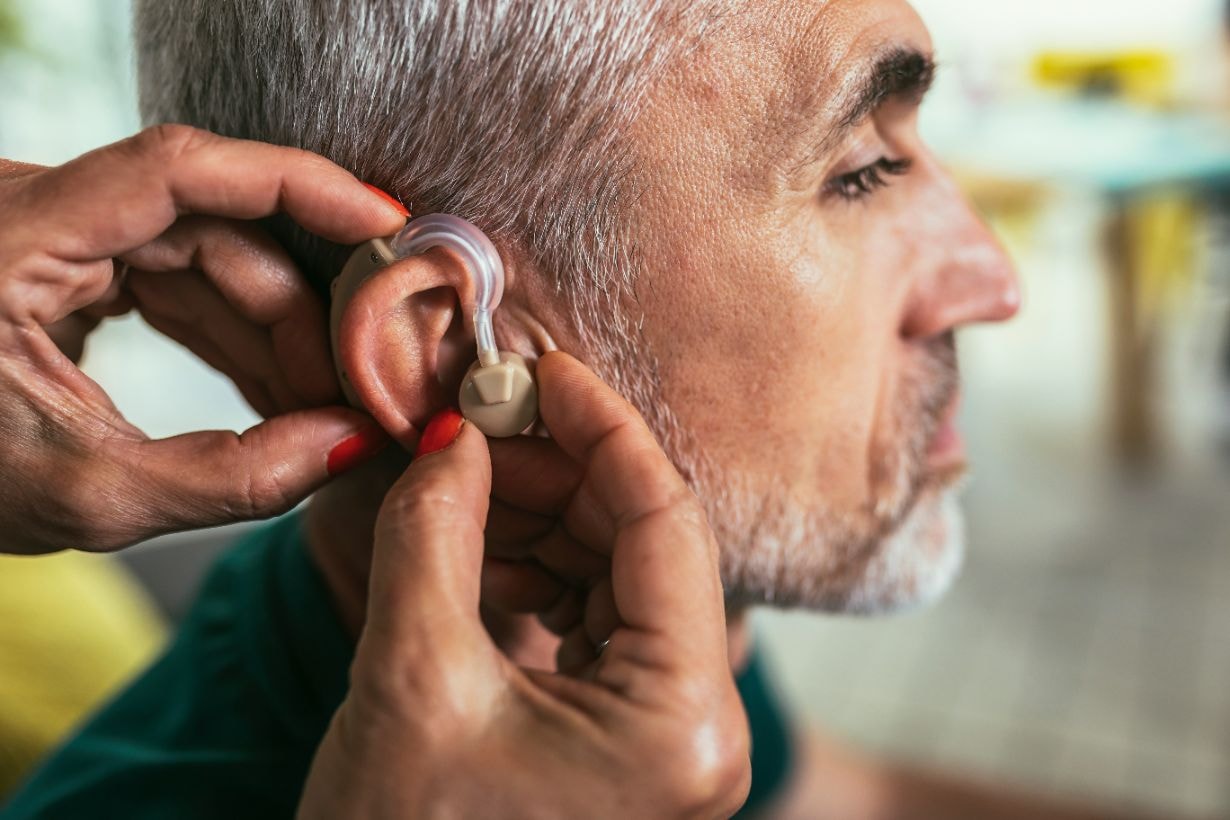 Medical professional puuting on a hearing aid for this patient