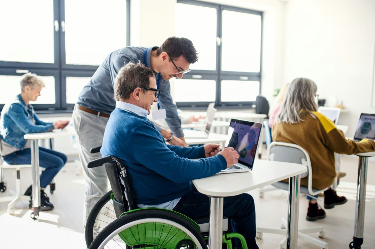 Disabled man being helped by instructor at a computer class